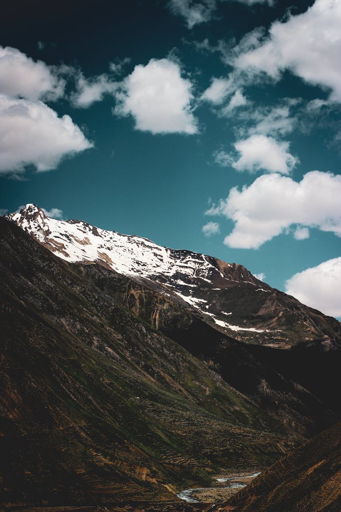 about-02 Breathtaking view of a snow-capped mountain under a clear sky with clouds.